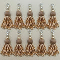 Set of eight gold and silver tassel charms on a beige background