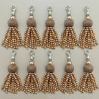 Set of eight gold and silver tassel charms on a beige background