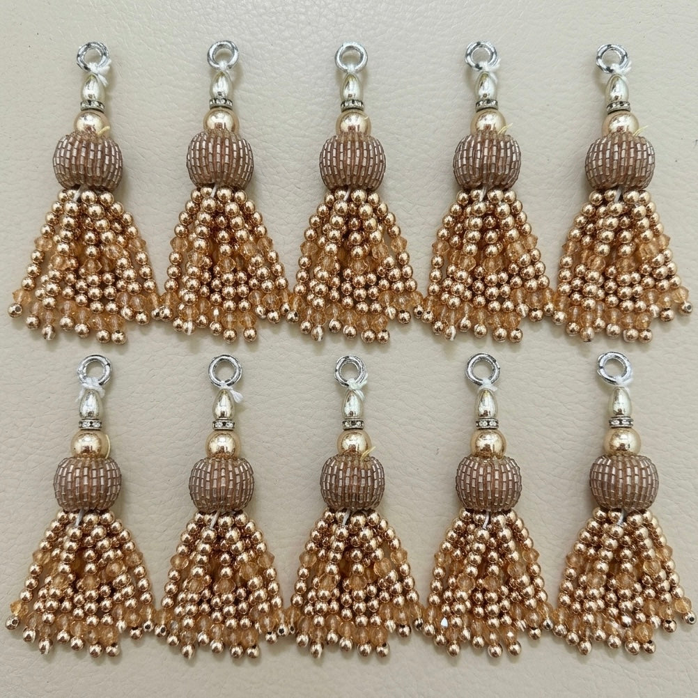 Set of eight gold and silver tassel charms on a beige background
