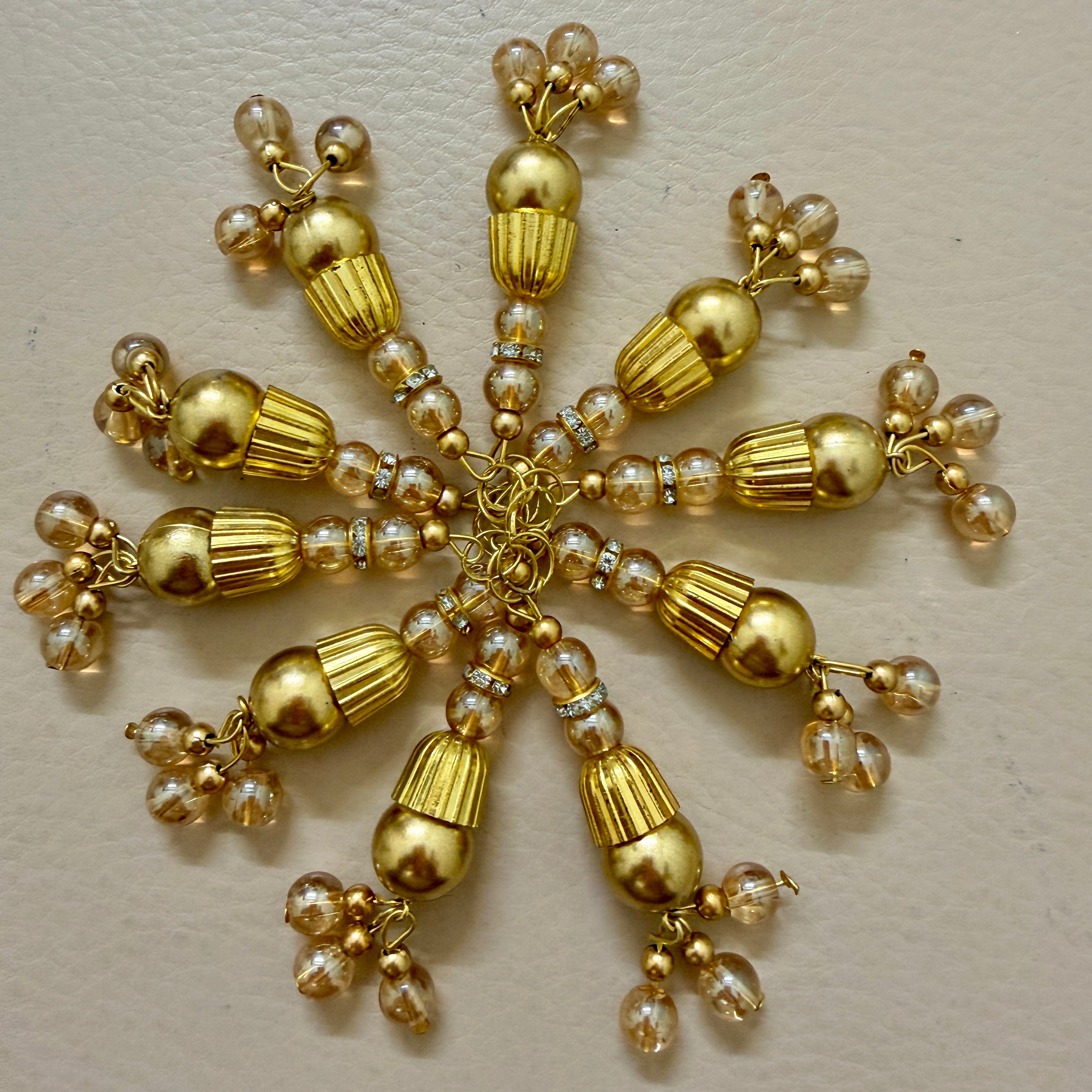 Gold and pearl decorative item on a beige background