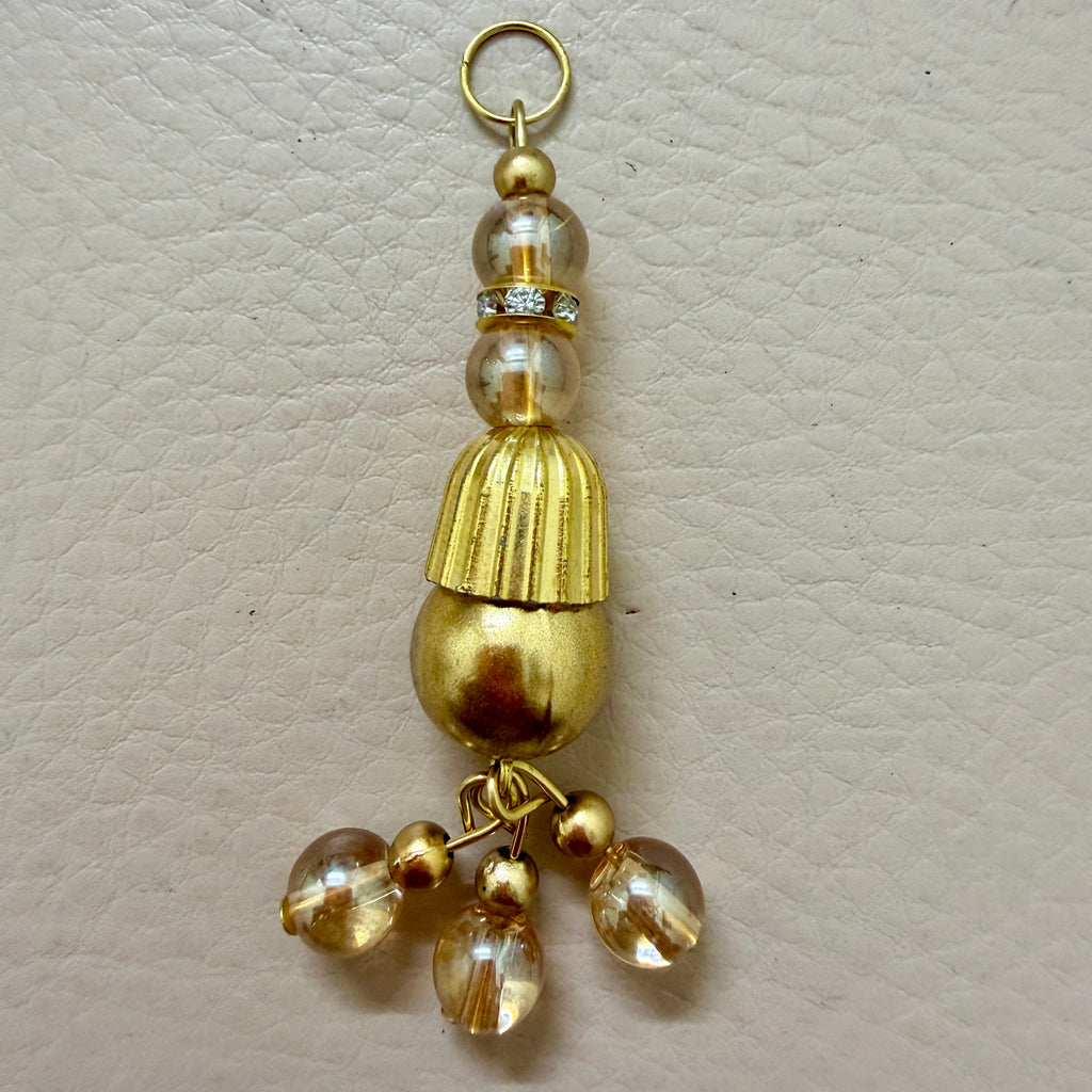 Gold tassel with beads on a beige background