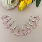 Decorative tassel charms on a beige surface with flowers in the background