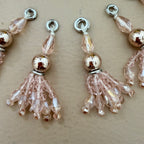 Beaded charms with pink and gold beads on a beige background