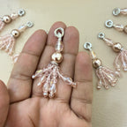 Beaded tassel charm held between fingers with more charms in the background.
