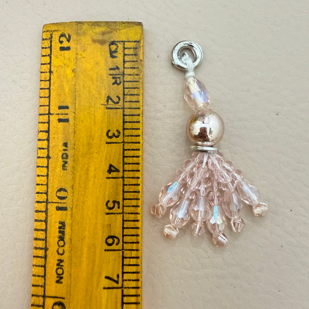 Jewelry charm next to a ruler on a beige background