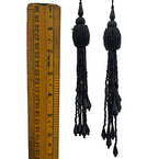 Black tassel earrings with a ruler for scale on a white background