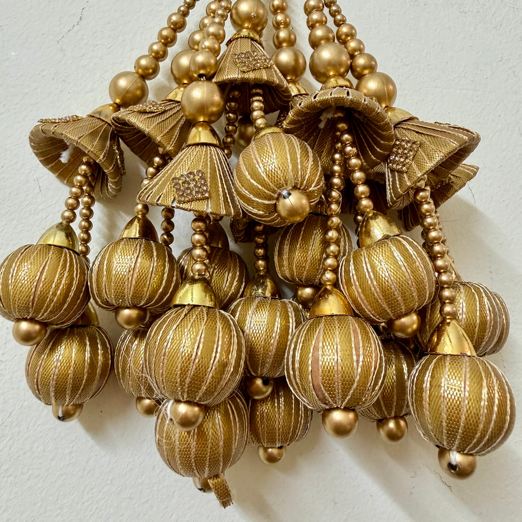 Decorative gold pendant with intricate design on a white background