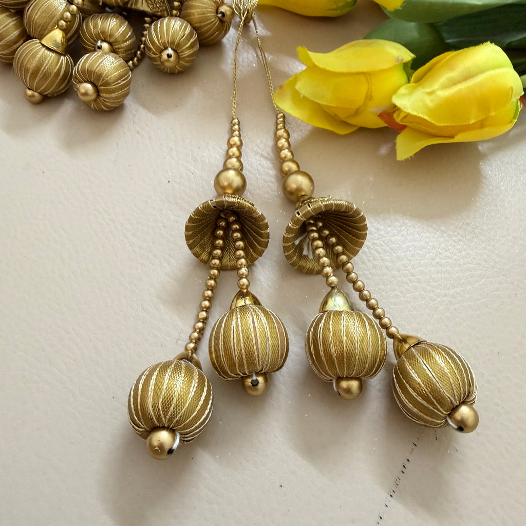 Gold earrings with beaded chains on a light background with yellow flowers.