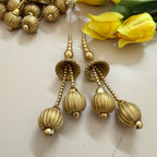 Gold earrings with beaded chains on a light background with yellow flowers.