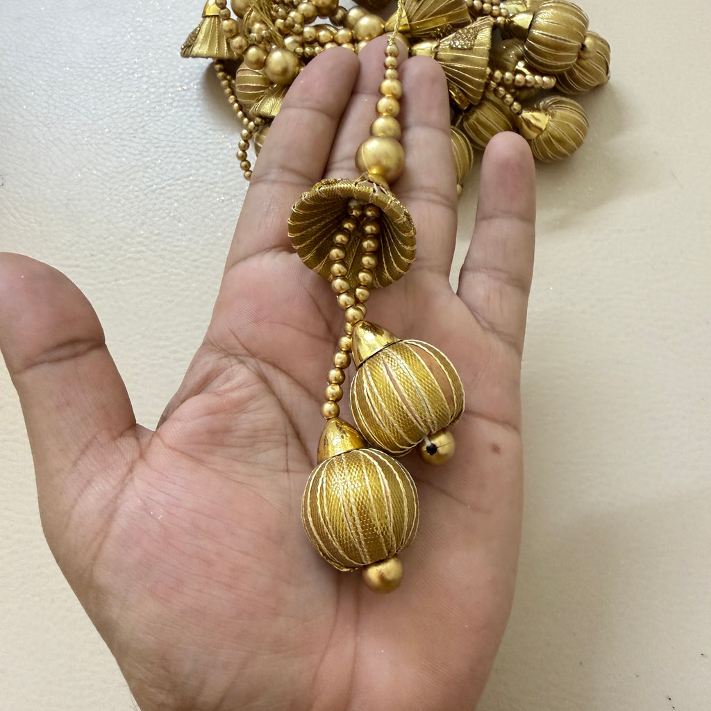 Gold necklace held in a hand against a plain background
