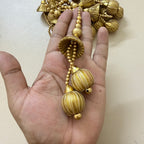 Gold necklace held in a hand against a plain background