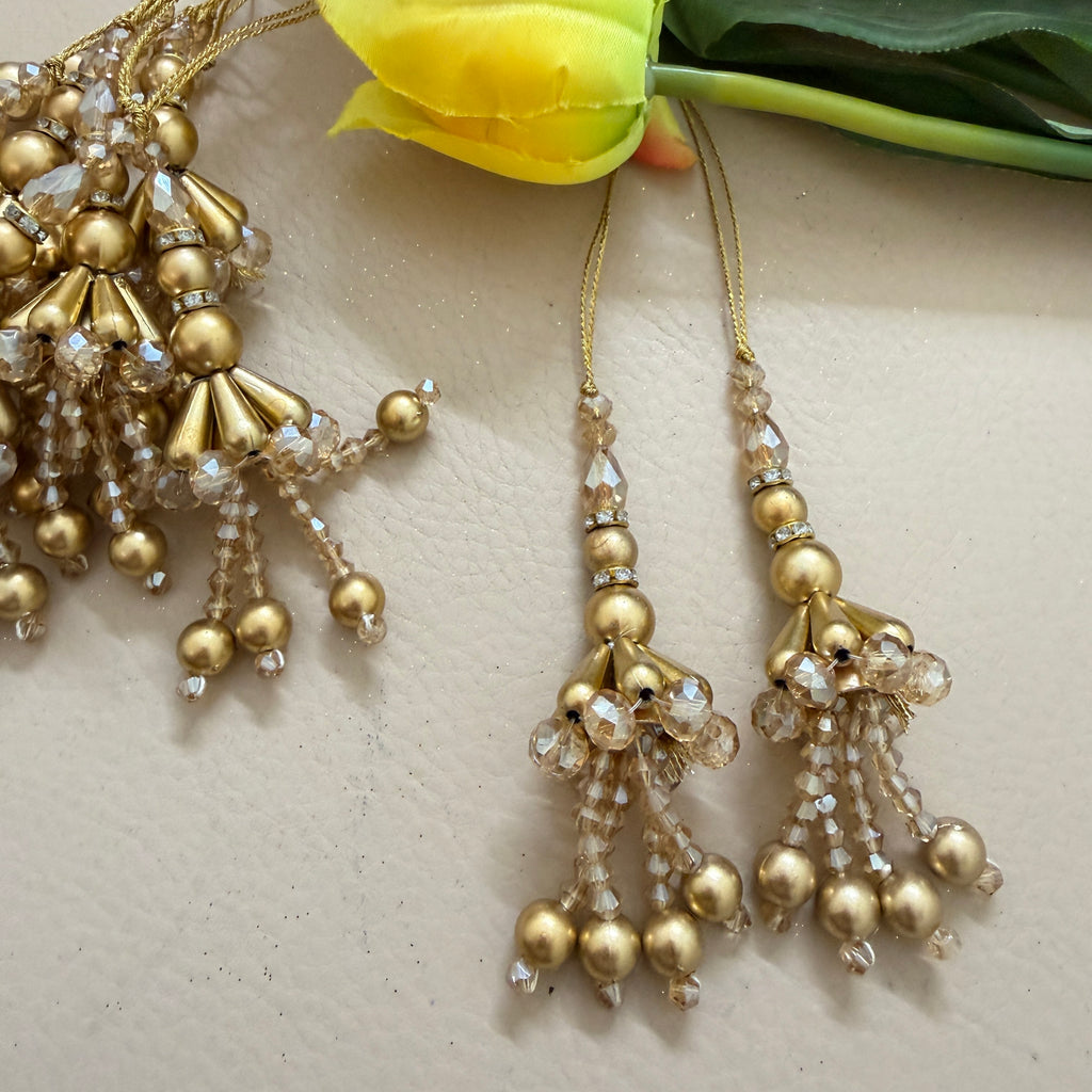Gold beaded earrings with clear stones on a light background