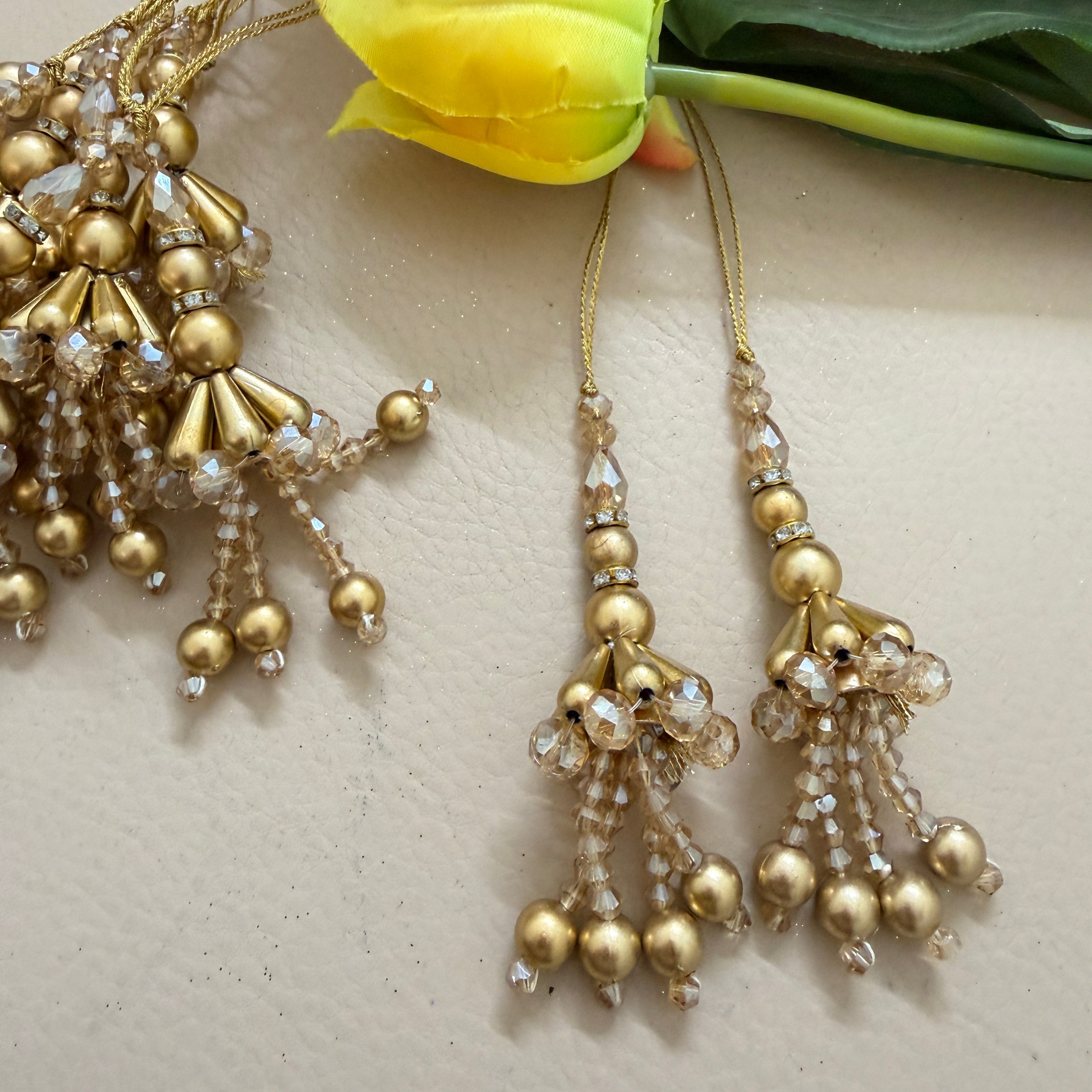 Gold beaded earrings with clear stones on a light background