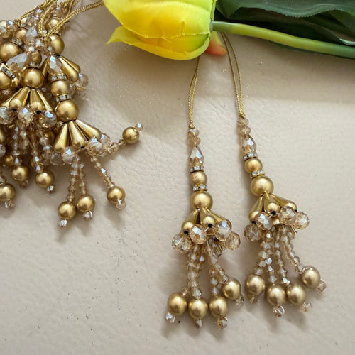 Gold beaded earrings with clear stones on a light background