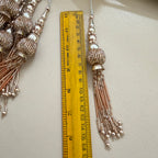 Decorative tassel with a ruler for scale on a light background