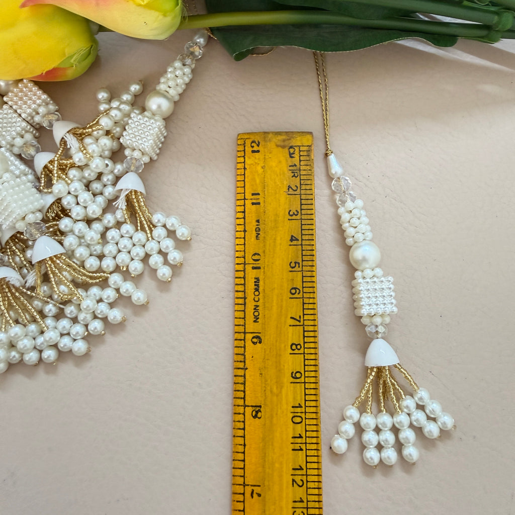 Pearl and gold tassel with a ruler for scale on a light background
