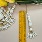 Pearl and gold tassel with a ruler for scale on a light background
