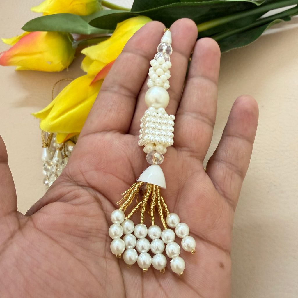 Pearl and gold decorative item held in a hand with yellow flowers in the background