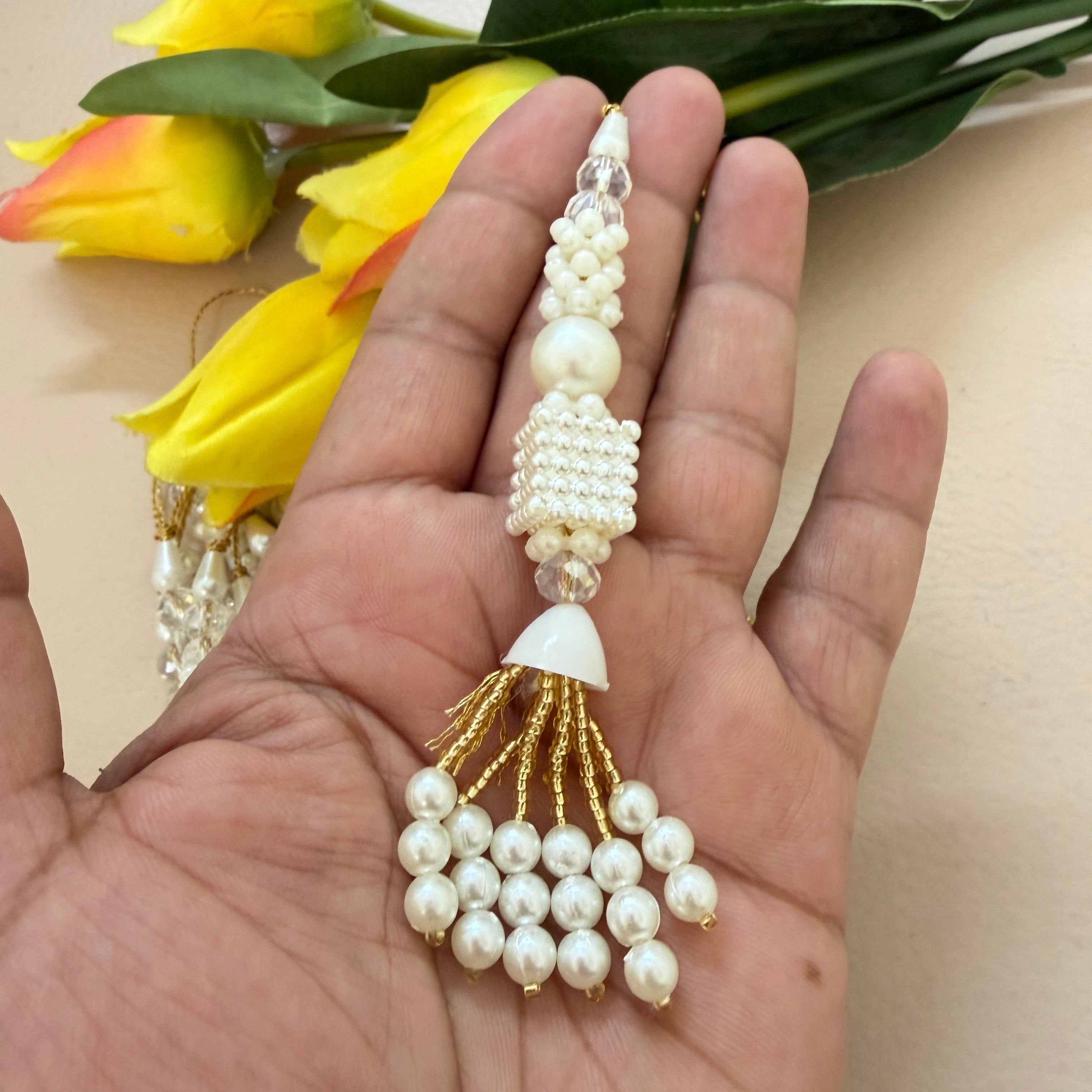 Pearl and gold decorative item held in a hand with yellow flowers in the background