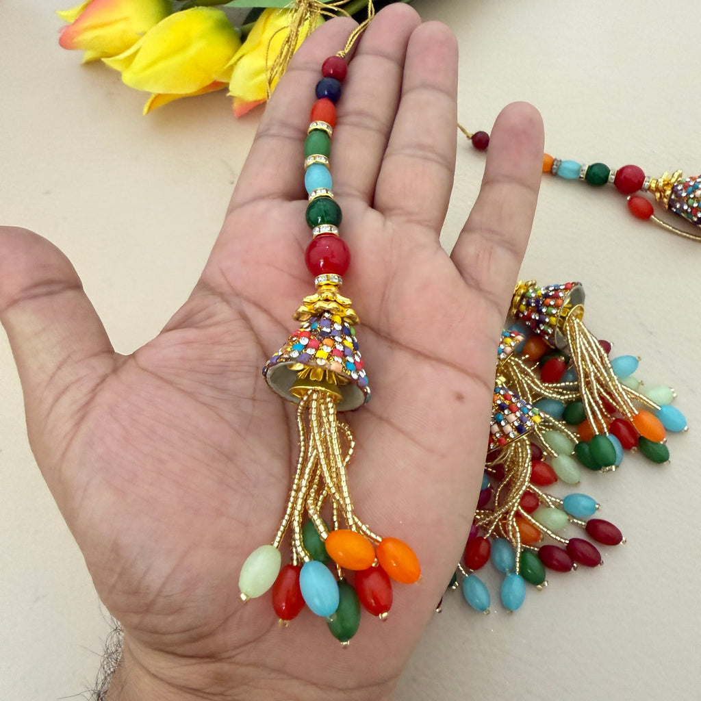 Colorful beaded decorative item held in a hand with flowers in the background