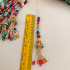 Colorful beaded tassel with a ruler for scale on a light background