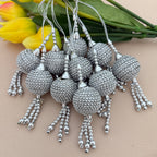 Silver beaded tassels with a beige background and yellow flowers.