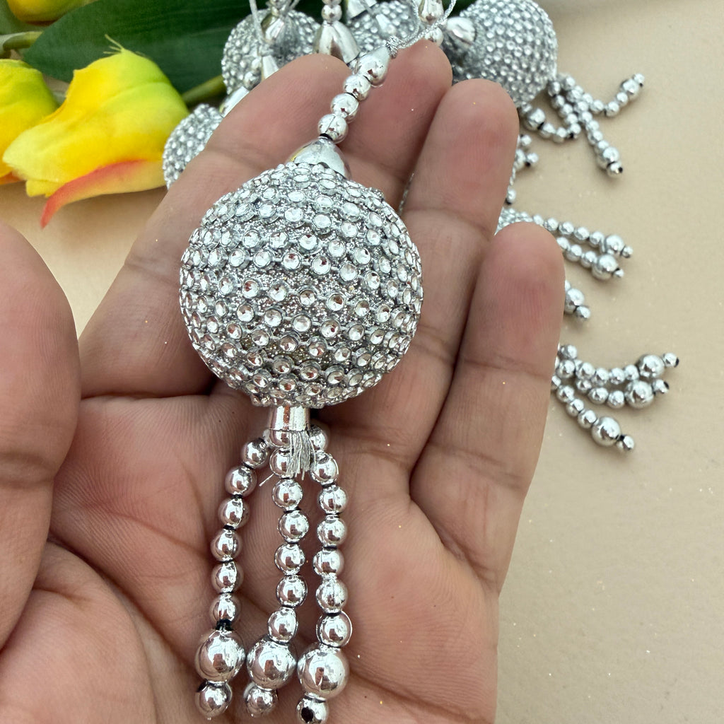 Silver beaded decorative item held in a hand with a blurred background