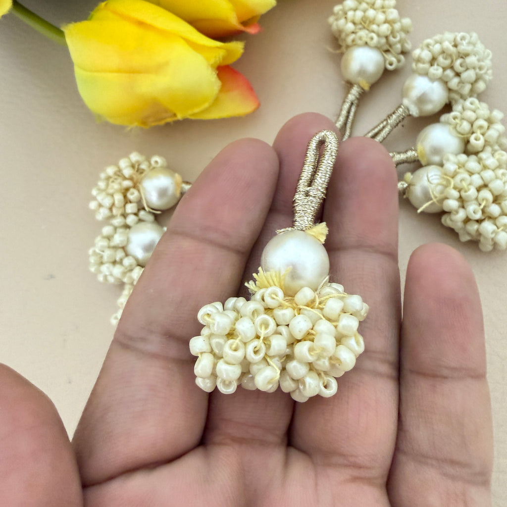 Pearl decorative item held between fingers with flowers in the background