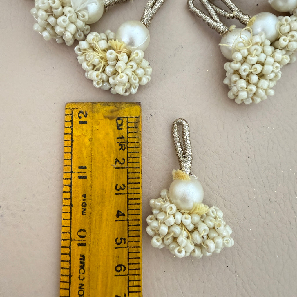 Pearl-like decorative elements with a ruler for scale on a neutral background