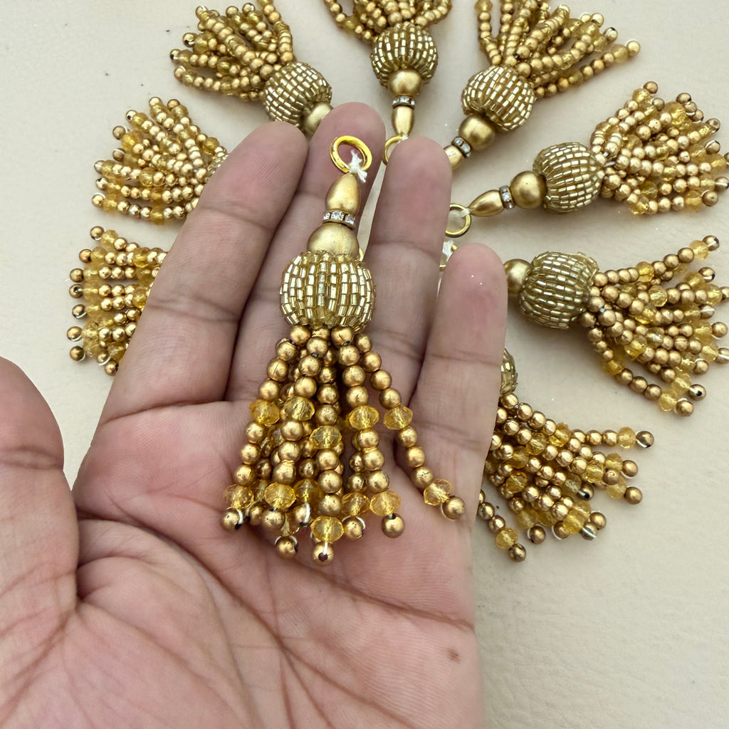 Gold tassel held between fingers with more tassels in the background