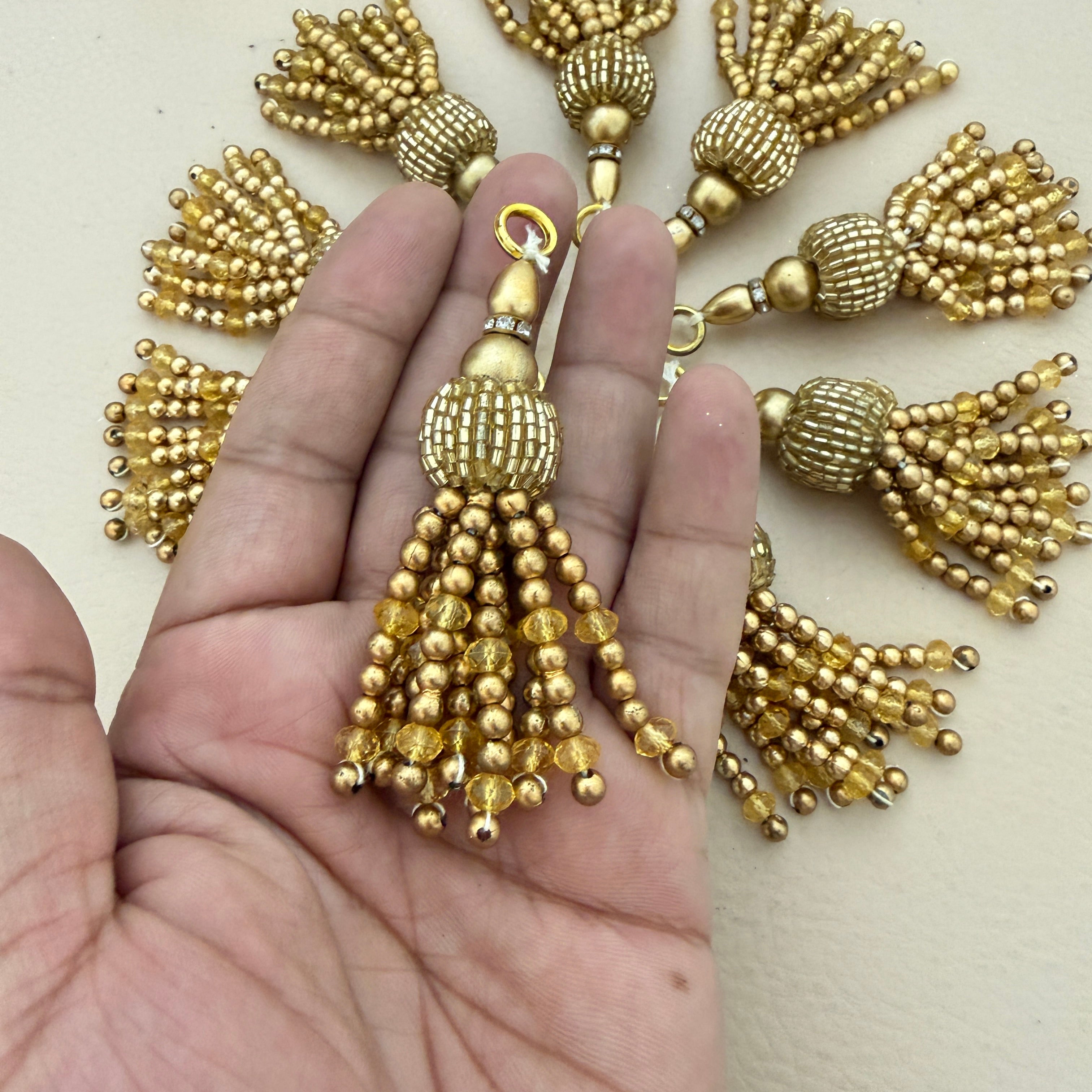 Gold tassel held between fingers with more tassels in the background