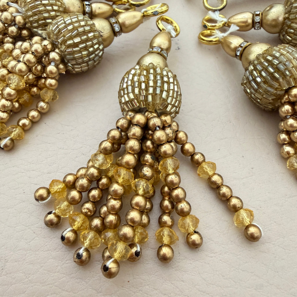 Gold beaded tassel earrings on a light background