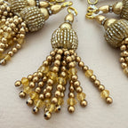 Gold beaded tassel earrings on a light background