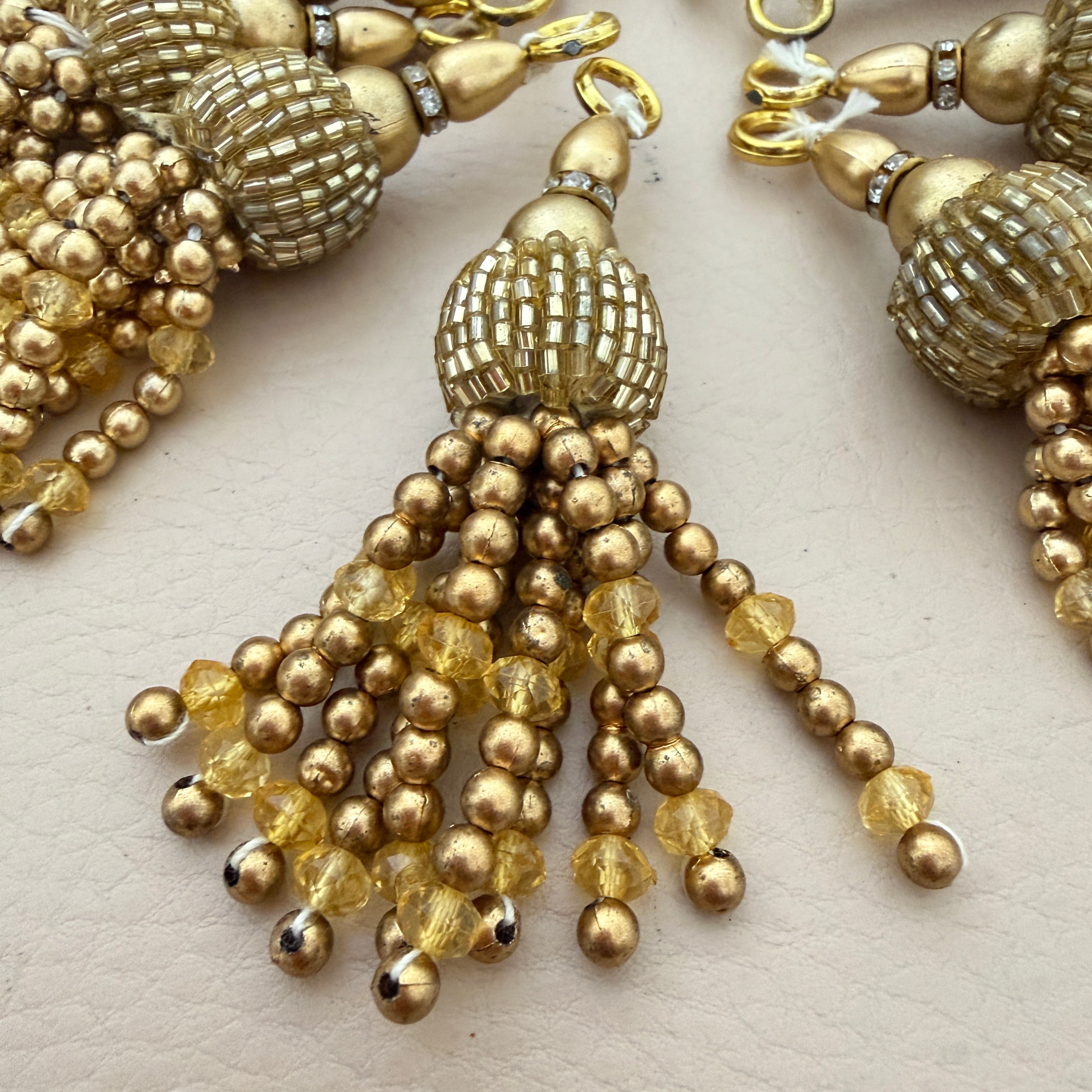 Gold beaded tassel earrings on a light background