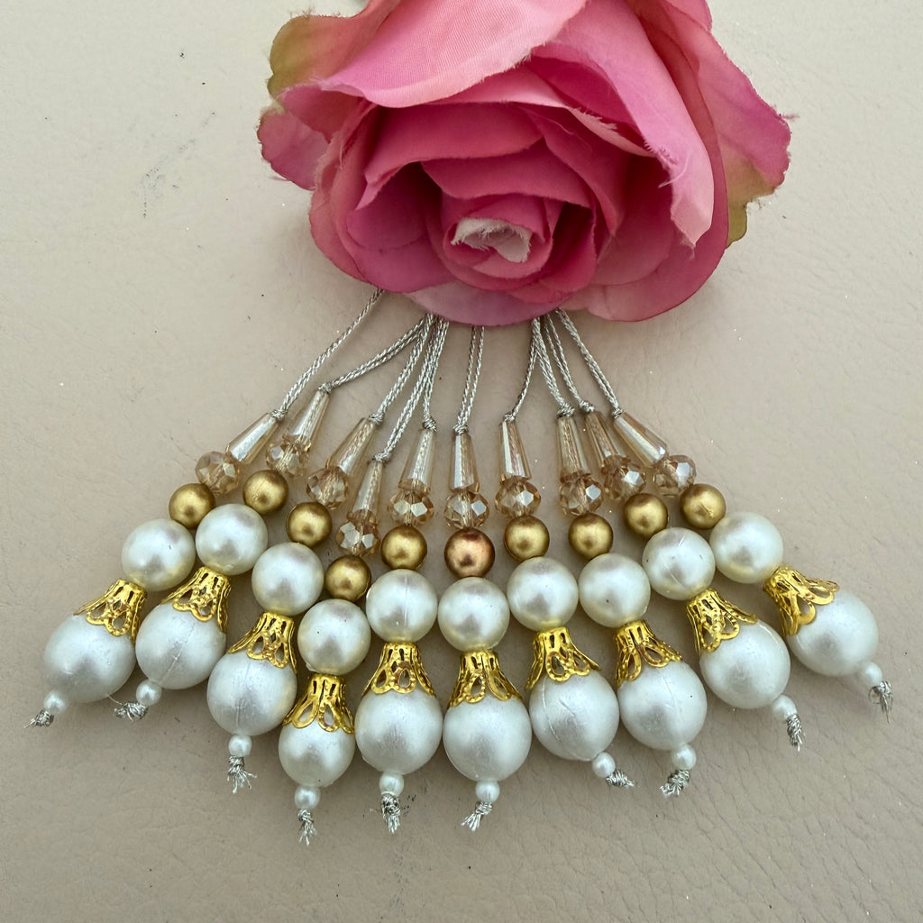 Set of pearl and gold beaded hair accessories with a pink rose on a beige background