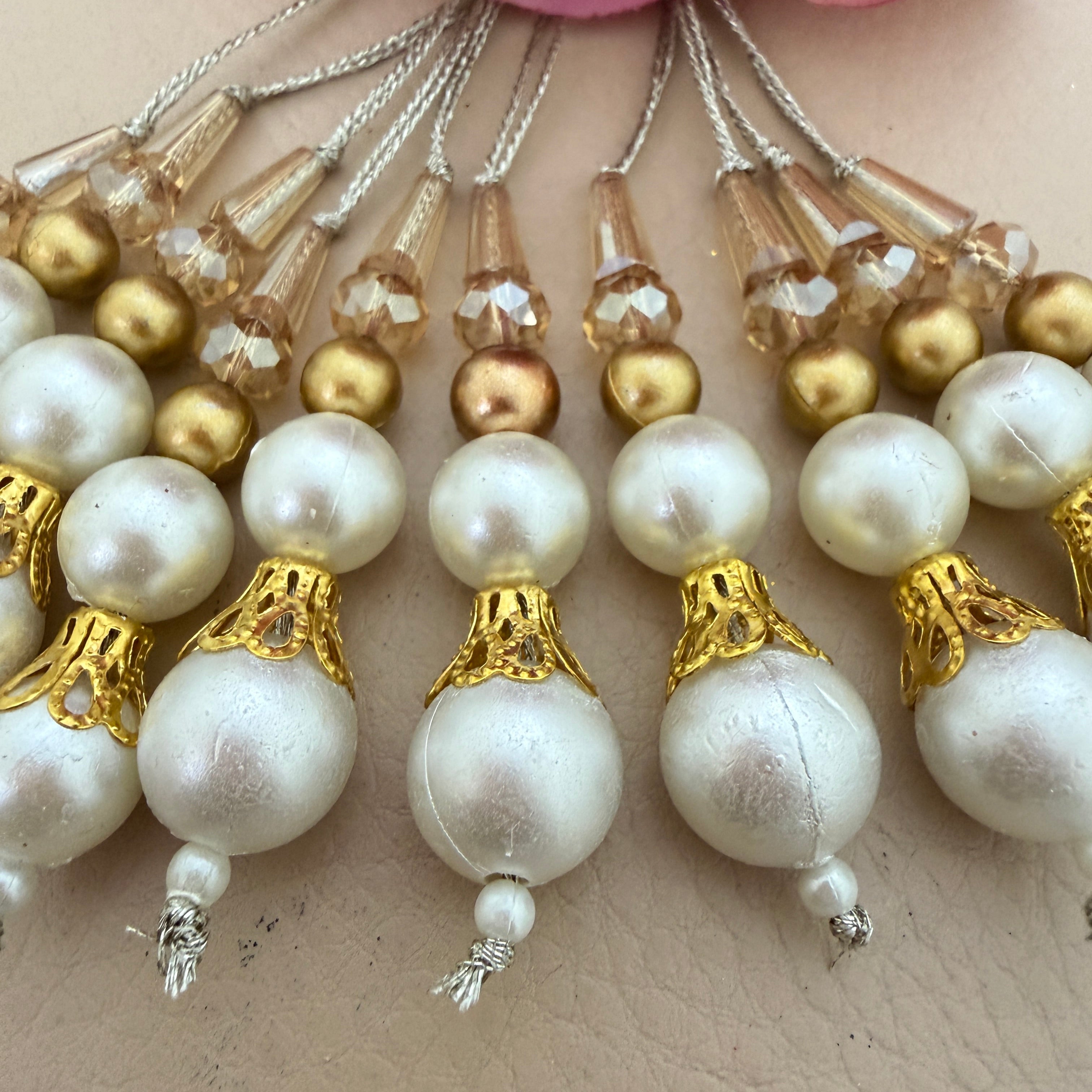 Close-up of pearl and gold bead decorations on a neutral background