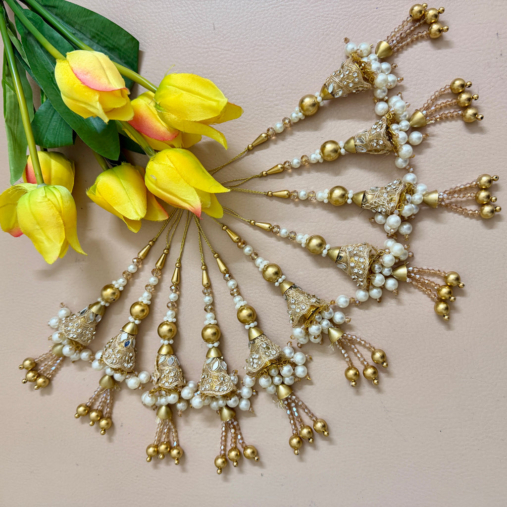 Decorative hair accessories with pearls and gold elements next to yellow tulips on a light pink background