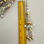 Decorative gold and pearl tassel with a ruler for scale on a light background