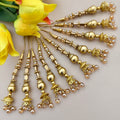 Gold jewelry with pearl accents on a light background with yellow flowers.