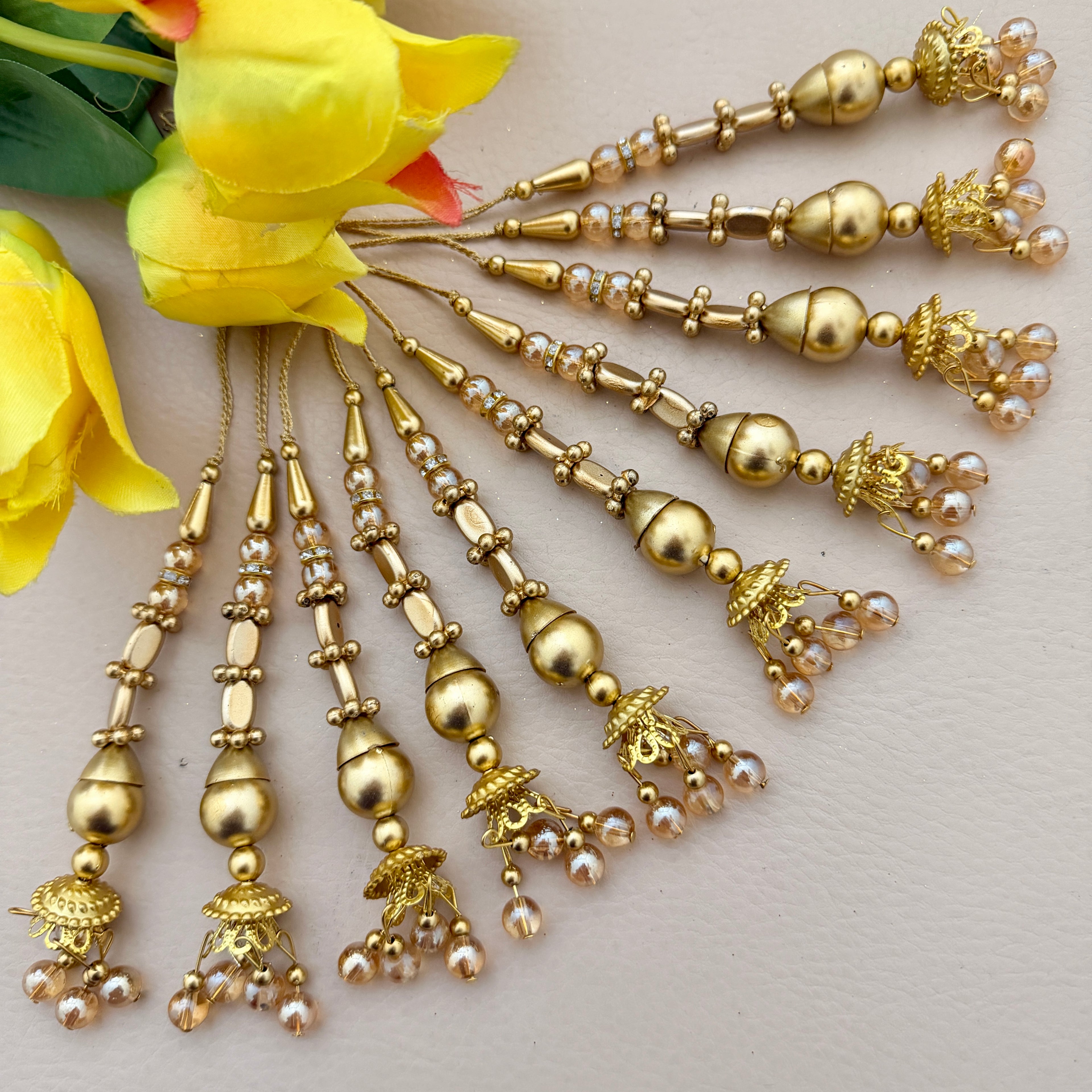Gold jewelry with pearl accents on a light background with yellow flowers.