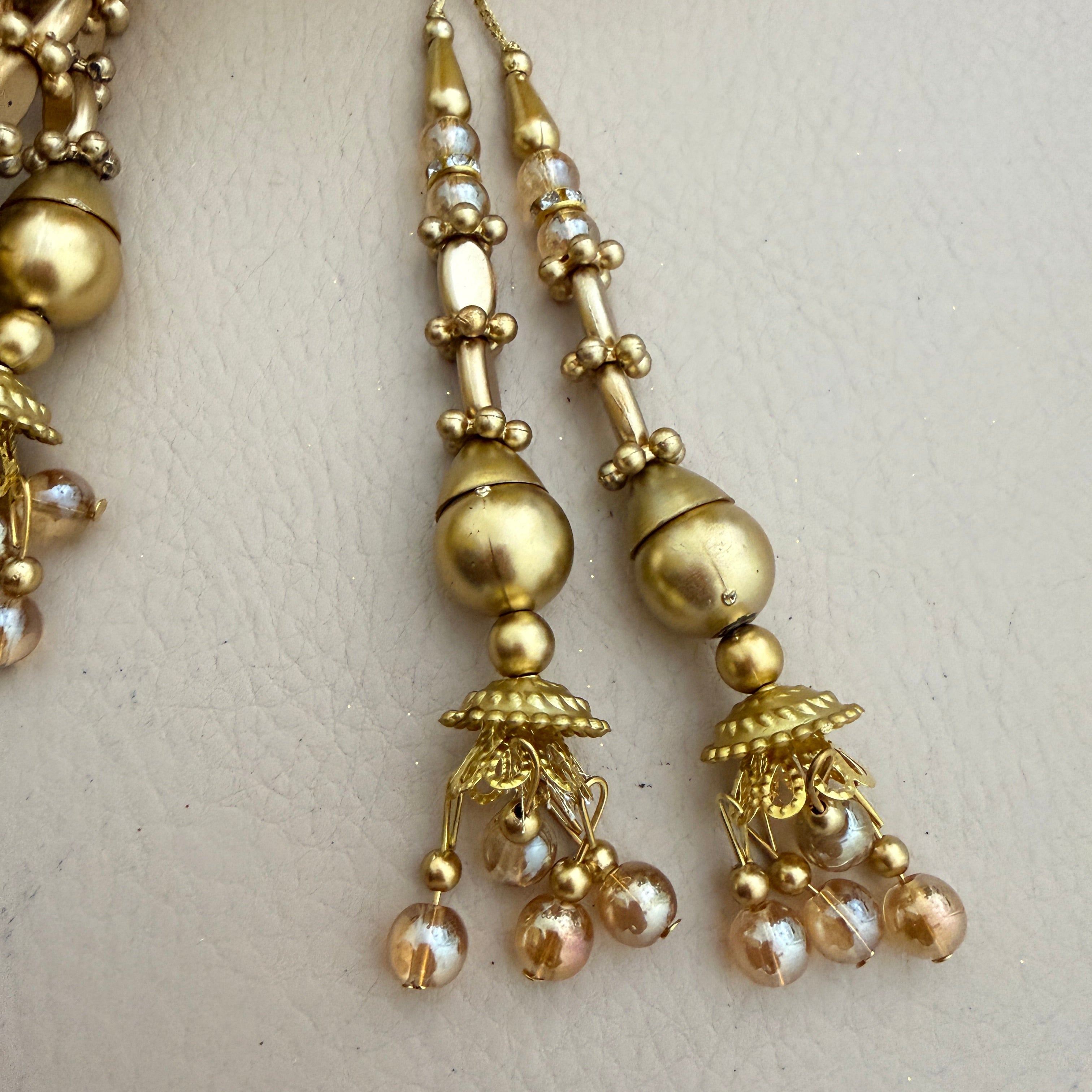 Gold earrings with pearl-like beads on a light background