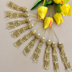 Gold tassels with pearls next to yellow tulips on a beige background