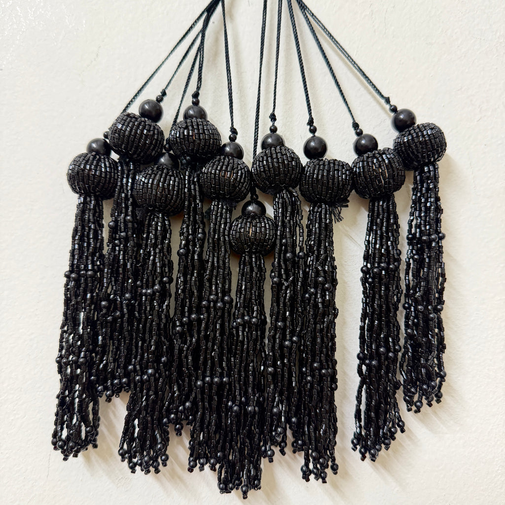 Black beaded tassel necklace on a white background