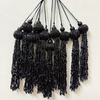 Black beaded tassel necklace on a white background