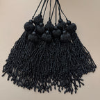 Black beaded tassel necklace on a beige background