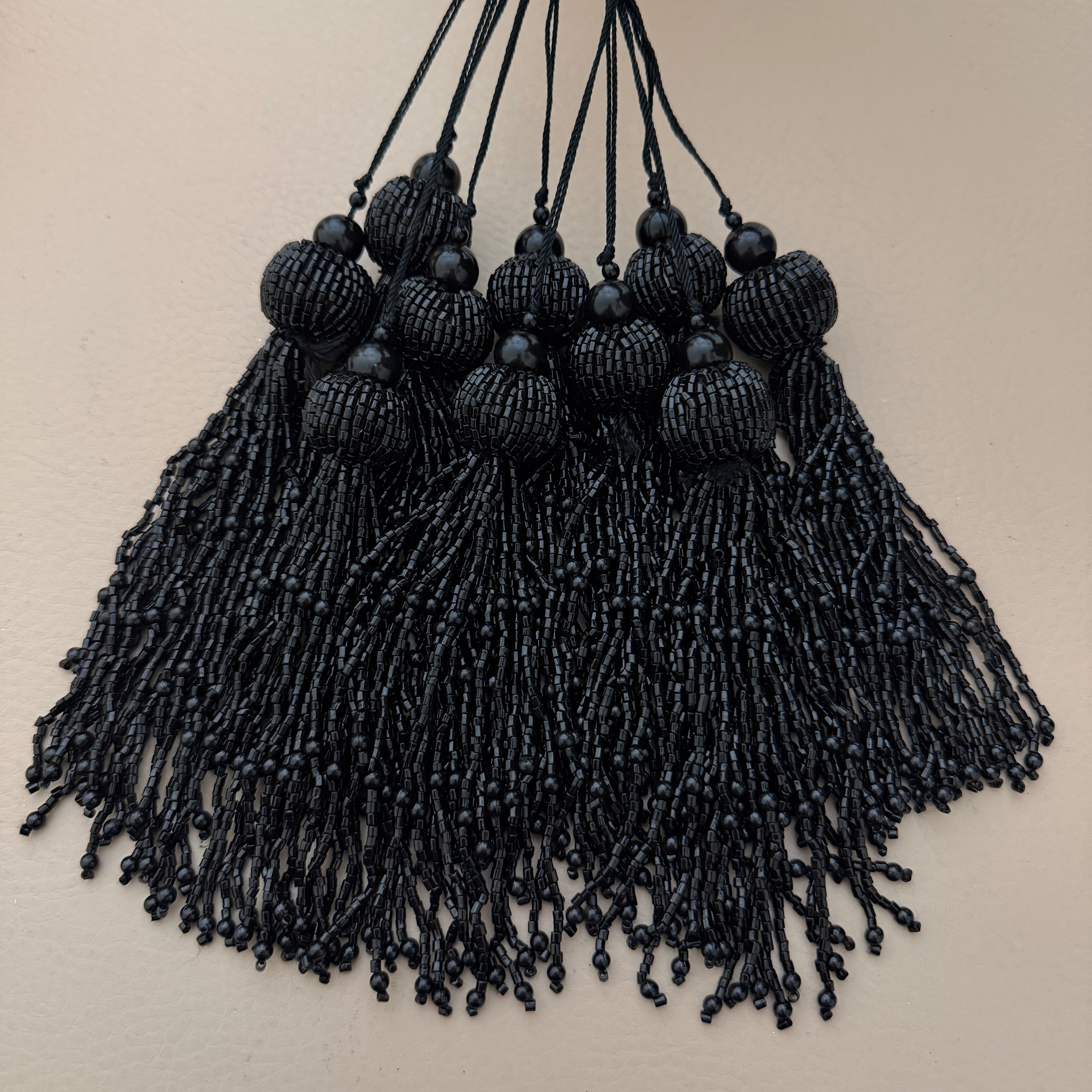 Black beaded tassel necklace on a beige background