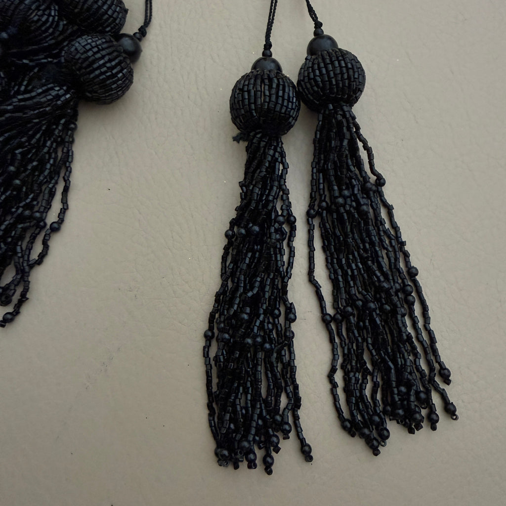 Black beaded tassels on a beige background