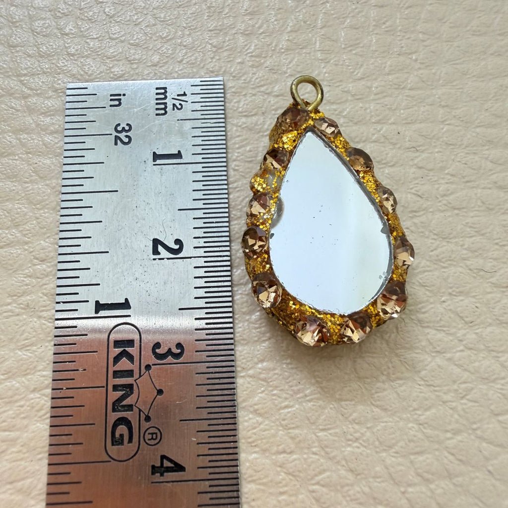 Close-up front and side views of gold and champagne teardrop mirror tassels