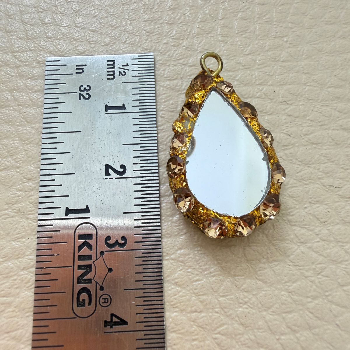 Close-up front and side views of gold and champagne teardrop mirror tassels