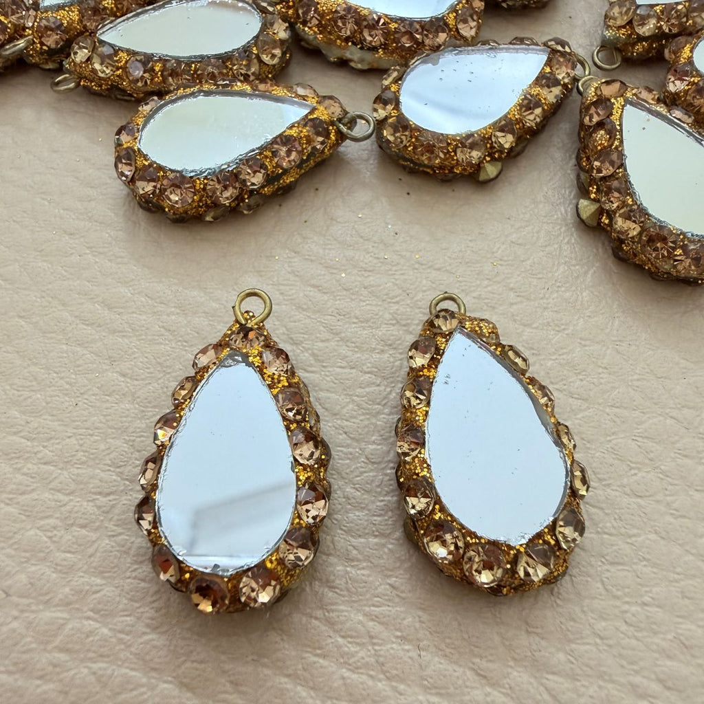 Small champagne rhinestone teardrop mirror tassel shown in hand for scale